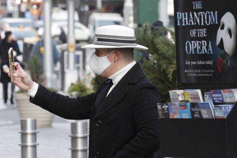 A man takes a photo near a poster for the Broadway show "Phantom of the Opera" in New York on Jan. 25, 2021. The show is closing in February after 35 years. File Photo by John Angelillo/UPI