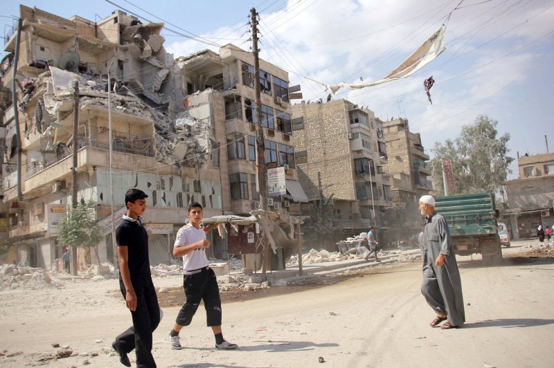 Residents walk by a building which was damaged by government airstrike in Aleppo, Syria, on Sept. 12, 2012. Russian airstrikes against rebel-held areas in northwestern Syria's Latakia province killed up to 45 people and injured dozens more on Monday, according to activists. File photo by Ahmad Deeb/UPI