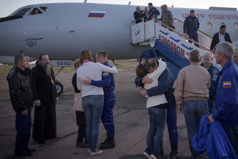 Cosmonaut Alexey Ovchinin of Roscosmos, left, and astronaut Nick Hague of NASA, right. embrace their families Thursday after landing at the Krayniy Airport in Baikonur, Kazakhstan. Hague and Ovchinin were aided by rescue forces after they were forced to abort a spaceflight to the International Space Station. NASA Photo by Bill Ingalls/UPI