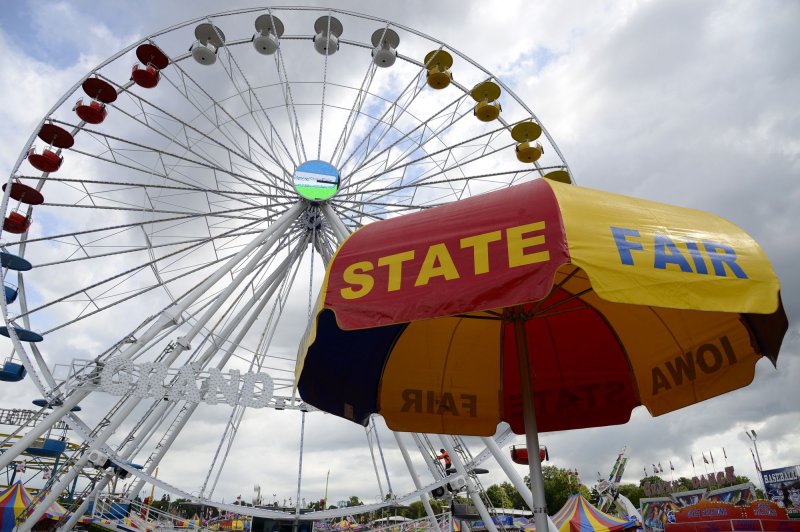An umbrella provides protection from threatening skies under a ferris wheel at the Iowa State Fair in Des Moines, Iowa, in 2019. This time of year marks peak season for State Fairs -- known for their unusual traditions. File Photo by Mike Theiler/UPI