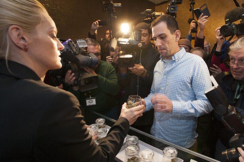Surrounded by a swarm of media in a small retail marijuana sales room, the first official recreational marijuana purchaser Sean Azzariti of Boston reaches for his first marijuana selection handed over by store owner Toni Fox at the 3D Cannabis Center in Denver on January 1, 2014. Colorado voters approved recreational marijuana use in 2012 with the first retail stores for recreational use opening this morning at 8 A.M.. UPI/Gary C. Caskey | <a href="/News_Photos/lp/0d25ebfb668479f44ee3c29514c5b5e5/" target="_blank">License Photo</a>