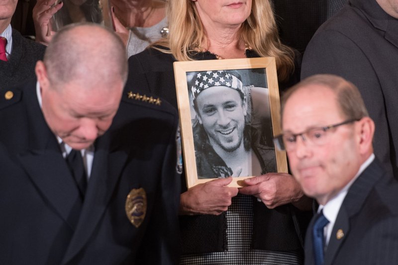 A woman holds a photo of a relative who died amid the opioid epidemic in the East Room of the White House on October 26 -- where President Donald Trump declared a public health emergency. Photo by Kevin Dietsch/UPI