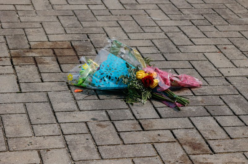 Blood stains and a bouquets of flowers mark the spot at Monroe Park where 18-year-old high school graduate Shawn Jackson and his stepfather, 36-year-old Renzo Smith were gunned down following the graduation ceremony for Huguenot High School in Richmond, Va., Tuesday night. Photo by Jemal Countess/UPI