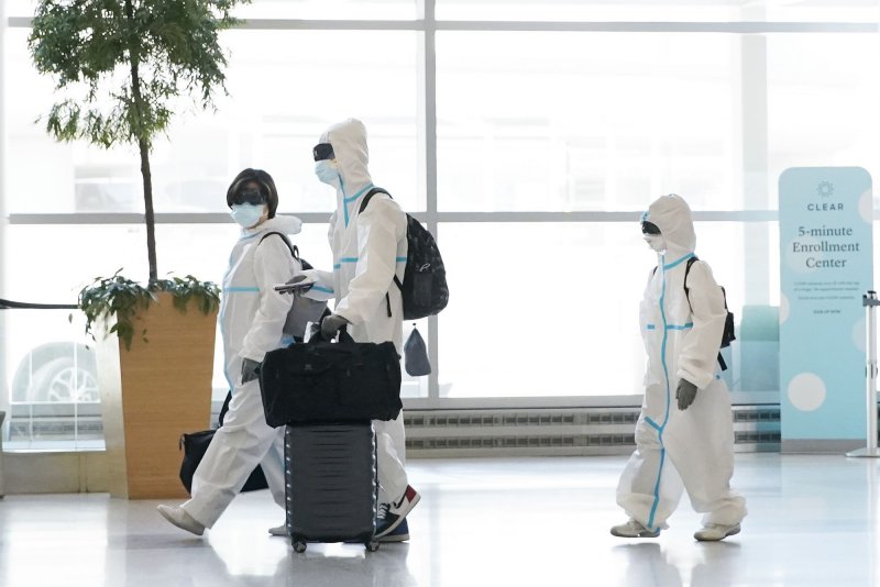 A man, woman and child walk through the San Francisco International Airport wearing full body plastic suits, face masks and goggles to protect against COVID-19 in August 2020.&nbsp; File Photo by John Angelillo/UPI