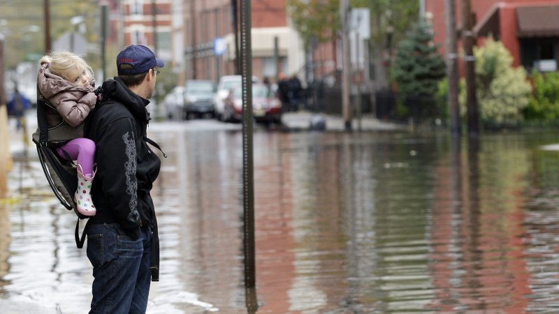 A man and child look out at flooded streets one day after Hurricane Sandy hits the north east section of the United States in Hoboken, New Jersey on October 31, 2012. The effect of the Sandy left large parts of New York City and New Jersey with out power and mass transit and officials at Consolidated Edison said it could be up to a week before power is fully restored. UPI/John Angelillo | <a href="/News_Photos/lp/c409800506bb76ffd38768fe0055b075/" target="_blank">License Photo</a>