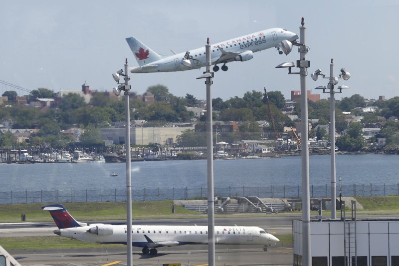 An Air Canada plane takes off over a Delta Airlines plane that remains on the runway at LaGuardia Airport in New York City on August 8, 2016. Photo by John Angelillo/UPI