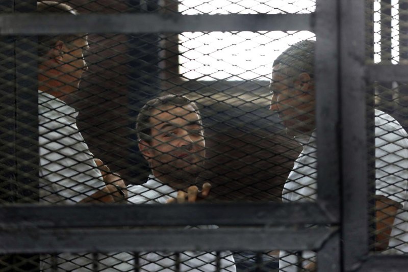 Three Al-Jazeera journalists Australian Peter Greste, Baher Mohamed and Canadian-Egyptian Mohamed Fahmy (L -R) stand behind caged bars with other defendants as they listen to the ruling at a court in Cairo, Egypt on June 23, 2014. The three were sentenced to seven years in prison on terrorism-related charges. The ruling brought worldwide criticism of the Egyptian court system. UPI/Karem Ahmed