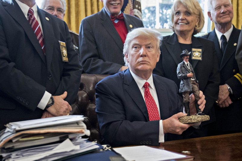 President Donald Trump receives a statue while meeting with a group of county sheriffs in the Oval Office of the White House on Tuesday. The president discussed various issues with the sheriffs, including the U.S. murder rate and drug trafficking. Pool photo by Andrew Harrer/UPI | <a href="/News_Photos/lp/a8d9fb168d7d90a10a18c76fa1281cba/" target="_blank">License Photo</a>