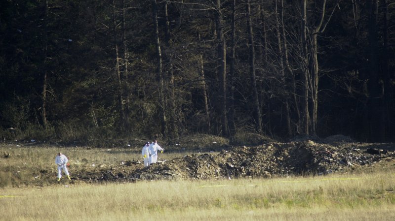 PIT2001091102 - 11 SEPTEMBER 2001 - SHANKSVILLE, PENNSYLVANIA, USA: One of the several investigators dressed in white and carrying yellow and red flags walk points to the crater caused by the crash of United Airlines flight 93 near Shanksville Pennsylvania, September 11, 2001, killing all 45 people on board. ac/Archie Carpenter UPI