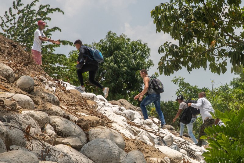 Migrants follow a smuggler after riding an inflatable raft on the Suchiate River from Tecun Uman, Guatemala, to Ciudad Hidalgo, Mexico, on May 9, 2019. The Biden administration is expelling migrants who cross the border illegally under Title 42. File Photo by Ariana Drehsler/UPI