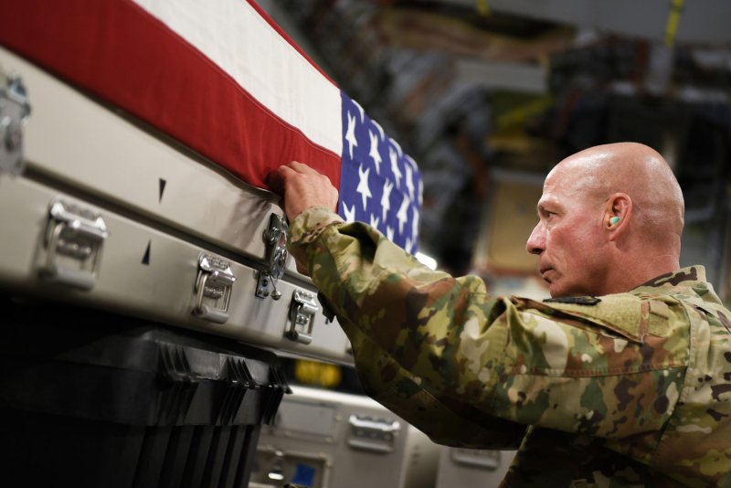 U.S. Army Sgt. 1st Class Eric Feltz, mortuary affairs specialist assigned to the Defense POW/MIA Accounting Agency, secures a U.S. flag onto a transfer case aboard an Air Force plane en route to Joint Base Pearl Harbor-Hickam, Hawaii, from Osan Air Base in Korea on Wednesday. The cases contain possible remains of service members lost during the Korean War. Photo by Sgt. 1st Class David J. Marshall/U.S. Army