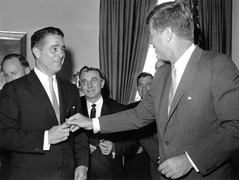 President John F. Kennedy (R) hands a pen to his brother-in-law, Sargent Shriver, after signing a bill giving the Peace Corps permanent status in this September 22, 1961 file photo. Shriver was appointed the Peace Corps' first director. At center is Illinois Congressman Roman C. Pucinski. UPI File Photo