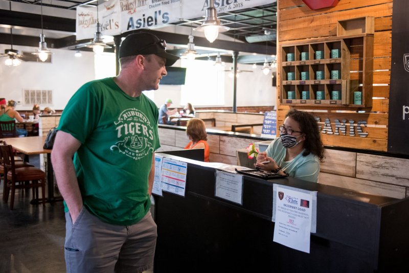 An employee at the front desk of Asiel's restaurant in Clute, Texas takes a customer's phone number as he waits for an open table in May as restaurants were operating with limited capacity. File Photo by Trask Smith/UPI