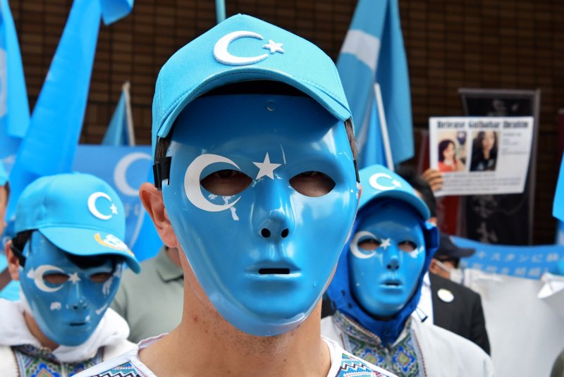 Demonstrators wear masks bearing the flag of East Turkestan during a pro-Uyghur protest. President Joe Biden on Thursday signed the Uyghur Forced Labor Prevention Act into law, banning imports from China's Xinjiang region unless importers can prove the products were not made with forced labor. File&nbsp;Photo by Keizo Mori/UPI
