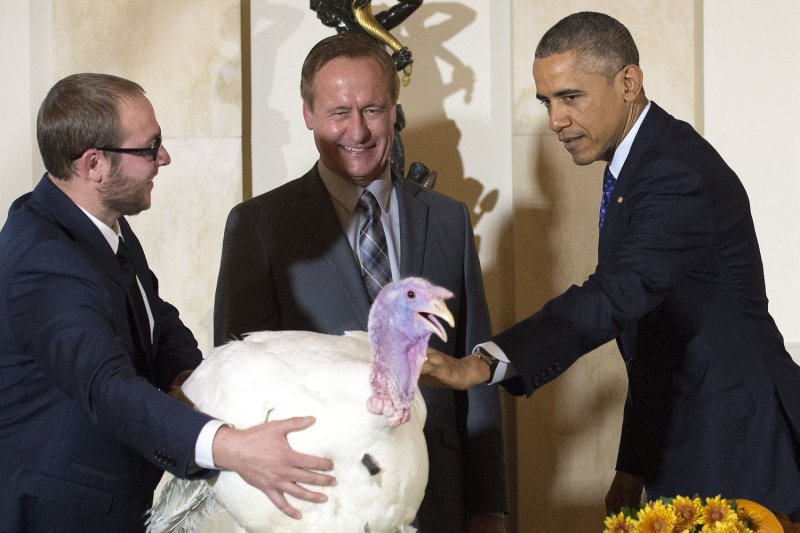 President Barack Obama pardons Cheese, the 2014 National Thanksgiving Turkey, as National Turkey Federation Chairman Gary Cooper (center) and his son Cole restrain it, during a ceremony at the White House on November 26, 2014 in Washington, D.C. Cheese and a turkey alternate named Mac, will be on display for visitors at their permanent home at Morven Park’s “Turkey Hill,” the historic turkey farm located at the home of former Virginia Governor Westmoreland Davis in Leesburg, Virginia. UPI/Kevin Dietsch