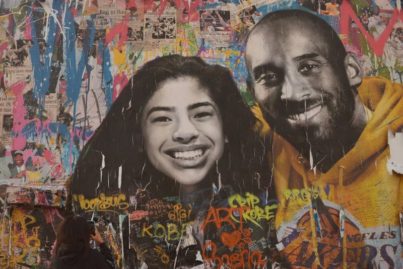 A visitor from Atlanta records a mural honoring Kobe Bryant and his daughter Gianna Bryant in Los Angeles on&nbsp; January 25. Los Angeles County is considering a settlement of $1.25 million each for two families involved in the helicopter crash the took their lives. File Photo by Jim Ruymen/UPI.