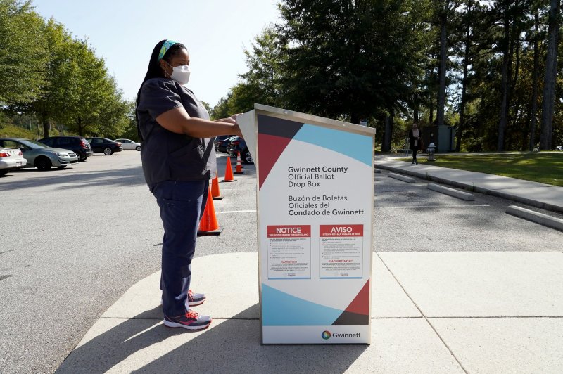 Nikara Paniagua drops her absentee ballot in a drop box on Election Day at Shorty Howell Park in Lawrenceville, Ga., on November 3, 2020. In Arizona, a judge has limited the activities of the group watching such drop box polling places. File Photo by Tami Chappell/UPI