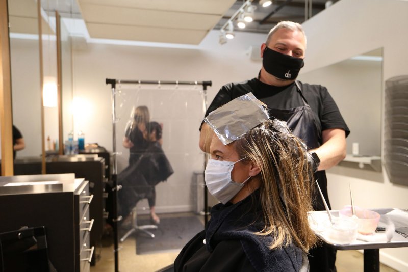 Stylist Jason Owen colors a customer's hair on May 18 at Dominic Michael Salon in Clayton, Mo., which has introduced multiple protective measures to guard against the coronavirus. Photo by Bill Greenblatt/UPI