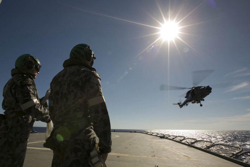 Crew members aboard the Australian Navy ship HMAS Success watch as a helicopter participates in a Replenishment at Sea with the Royal Malaysian Navy ship KD LEKIU in the southern Indian Ocean during the continuing search for Malaysia Airlines jetliner missing in the Indian Ocean, about 1,000 miles off the coast of Perth, Australia. The U.S. Navy "towed pinger locator" connected to the Ocean Shield picked up signals consistent with that of the missing jetliner it was announced April 7, 2014. (UPI/ David Connolly/Australian Defense Force)