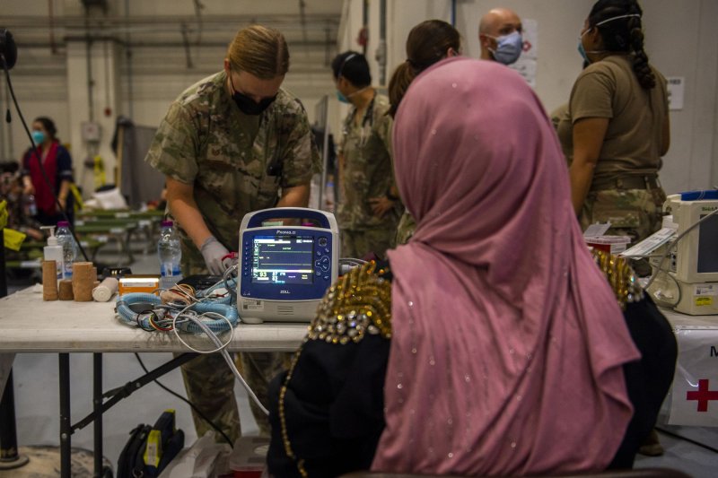 An Airman from the 379th Expeditionary Medical Group provides medical care for Afghanistan evacuees at a hangar, on August 19, 2021. On Tuesday, the last Afghan evacuees stationed at Virginia's Fort Pickett were resettled. File Photo by Airman 1st Class Kylie Barrow/U.S. Air Force/UPI