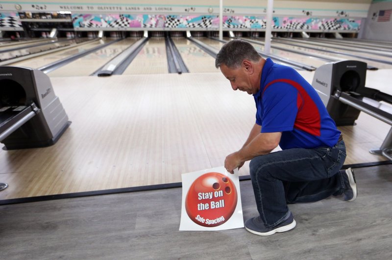Don Klackner, owner of&nbsp;Olivette Lanes in Olivette, Mo., prepares Tuesday to apply a sticker to the floor reminding bowlers to maintain proper distance to avoid potentially spreading the coronavirus disease. Photo by Bill Greenblatt/UPI