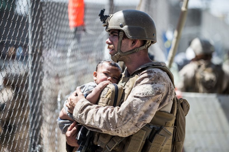 A U.S. Marine calms a child during an evacuation at Hamid Karzai International Airport in Kabul, Afghanistan, on August 26, 2021. A State Department report issued Friday found the United States didn't plan properly for a rapid collapse of the Afghan government. File Photo by Sgt. Samuel Ruiz/USMC/UPI