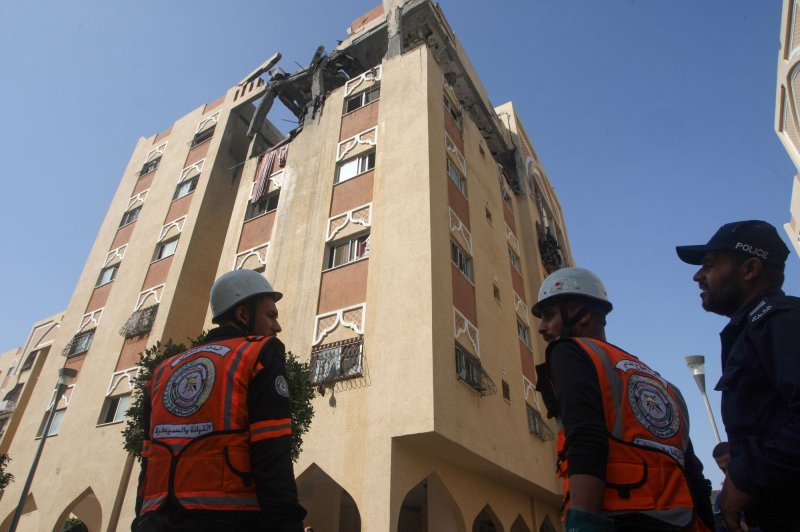 Civil defense workers stand by the residential building that Israel said housed an Islamic Jihad leader who was killed by Israeli strikes on Thursday morning. Photo by Ismael Mohamad/UPI