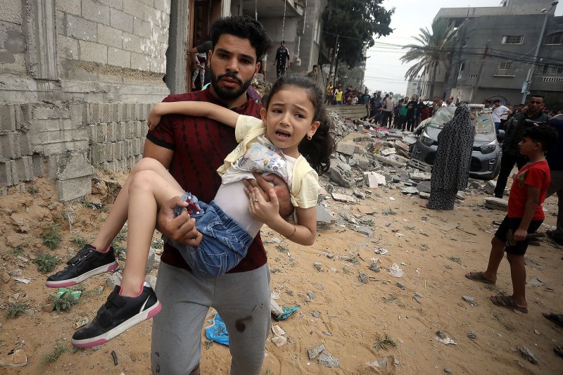 A man carries a crying girl in the aftermath of Israeli bombing on AL-mgary family houses in Rafah in the southern Gaza Strip on Sunday. Photo by Ismael Mohamad/UPI