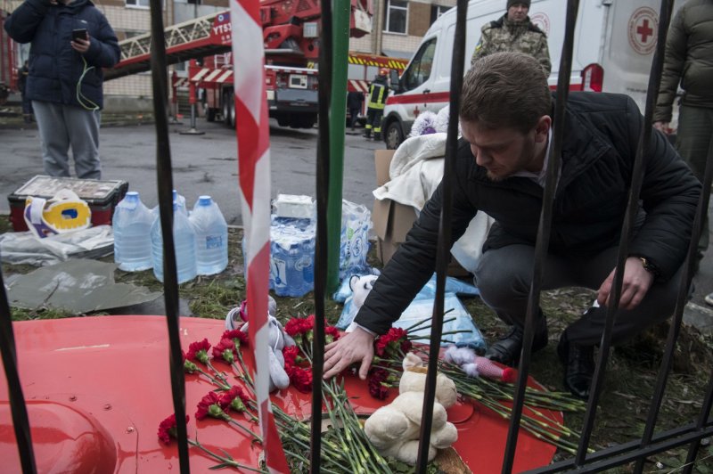 A man lays flowers at the site where a helicopter crashed Wednesday near a school in Brovary, outside the capital Kyiv, Ukraine, killing a cabinet minister and many others, including children. Photo by Vladyslav Musiienko/UPI
