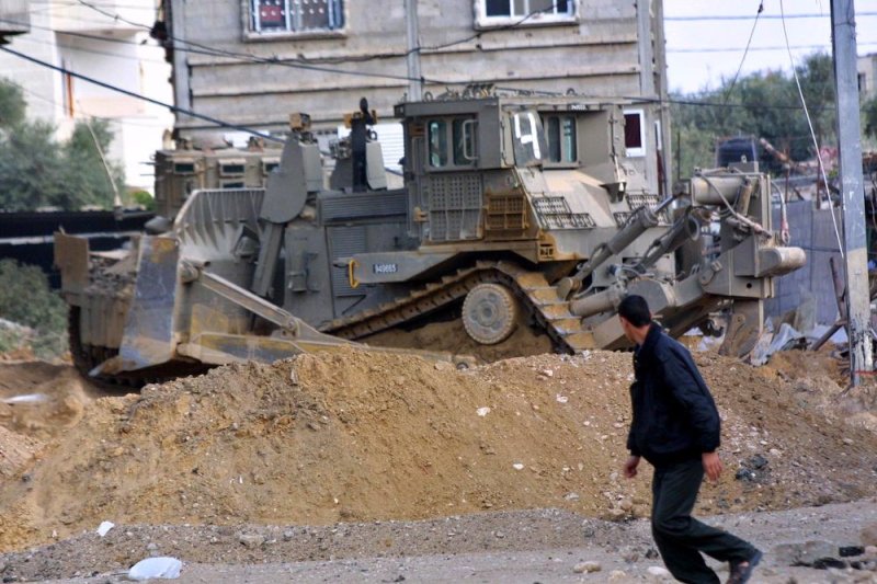 A Palestinian boy runs away from an Israeli army bulldozer during an army operation to uncover tunnels at the Rafah refugee camp April 3, 2004 in the southern Gaza Strip. The Israeli army periodically finds and destroys tunnels used, according to the army, by Palestinian militants to smuggle weapons and explosives from Egypt into the Gaza Strip. (UPI Photo/Ismael Mohamad) | <a href="/News_Photos/lp/0b784dd8b89eed097e5cfbb302e706af/" target="_blank">License Photo</a>