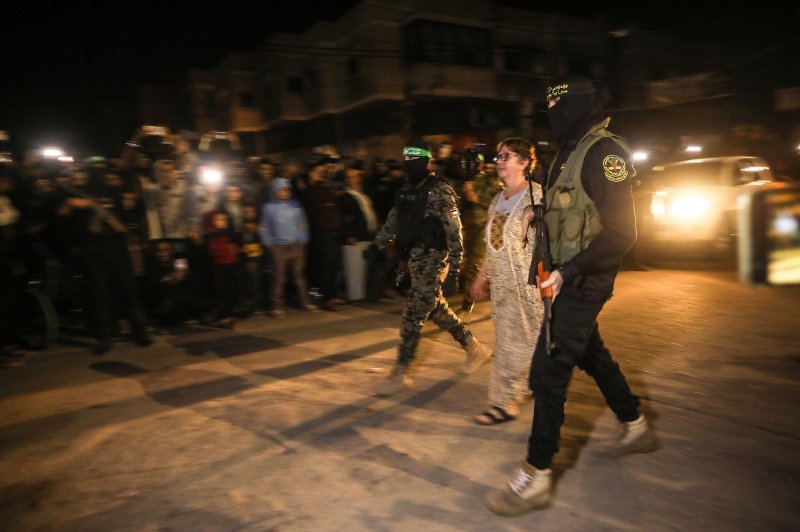 Hamas fighters accompany newly released hostages before handing them over to the Red Cross in Rafah in the southern Gaza Strip on Tuesday. UPI Photo