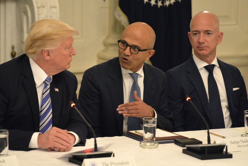 President Donald Trump listens to Microsoft CEO Satya Nadella (C) and Amazon CEO Jeff Bezos (R) at an American Technology Council roundtable discussion at the White House in June. File Photo by Mike Theiler/UPI
