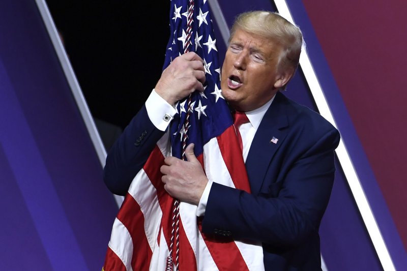 Then-President Donald Trump embraces an American flag on stage at the Conservative Political Action Conference on February 29, 2020, in National Harbor, Md. This year's conference will be held in Orlando, Fla., an will again feature Trump as the prime speaker. File Photo by Mike Theiler/UPI