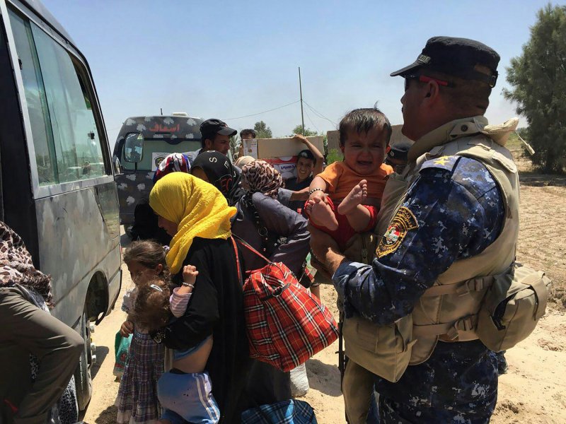 A member of the Iraqi Security Forces holds on tight to a young child as he and others assist civilians, fleeing their homes in Fallujah due to the increased fighting between government forces and militants with the Islamic State (ISIS), escape the embattled city on June 8, 2016. Photo by Abbas Mohammed/UPI