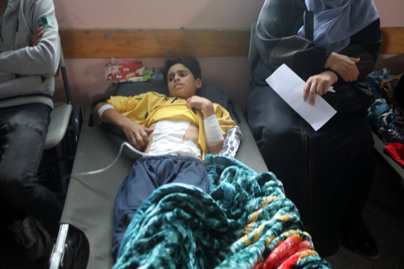 A wounded Palestinian boy from the Jabalia refugee camp lies on a bed after being transferred from the Indonesian Hospital in the north to a school in Khan Yunis on Wednesday. The Israeli military says it has destroyed 400 Hamas tunnels ahead of Thursday's anticipated hostage deal. Photo by Ismael Mohamad/UPI