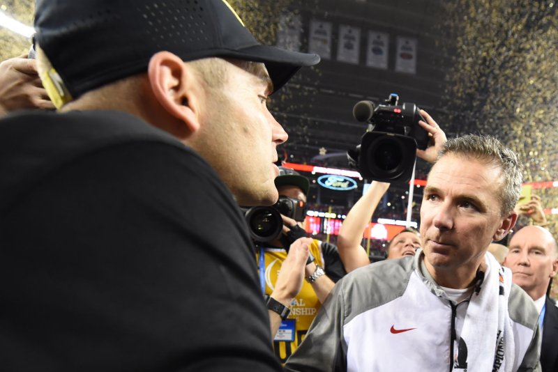 Ohio State Buckeyes head coach Urban Meyer, right, and Oregon Ducks head coach Mark Helfrich meet after Ohio State's 42-20 victory in the College Football Playoff National Championship, in Arlington, Texas on January 12, 2015. Photo by Ian Halperin/UPI