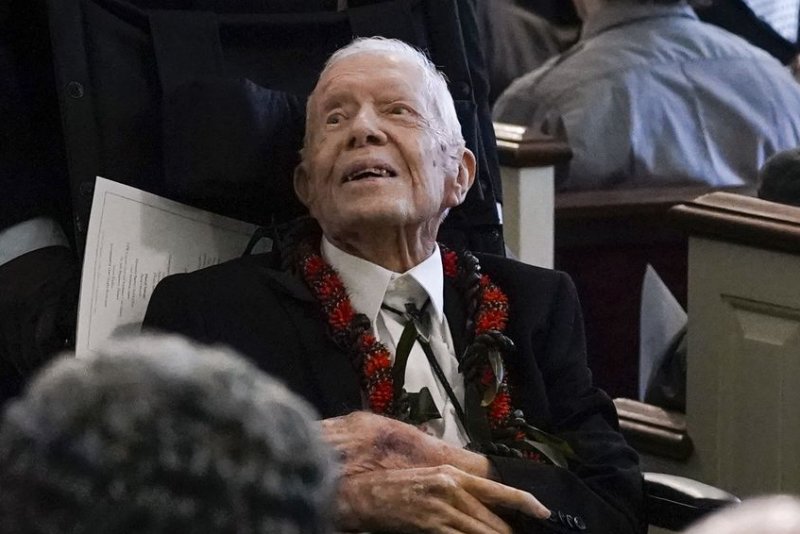 Former President Jimmy Carter attends the funeral service for his wife and former first lady Rosalynn Carter, at Maranatha Baptist Church on Wednesday in Plains, Ga. The former president, who is 99 years-old, wore a red lei to honor their time in Hawaii when he served in the Navy. Pool Photo by Alex Brandon/UPI
