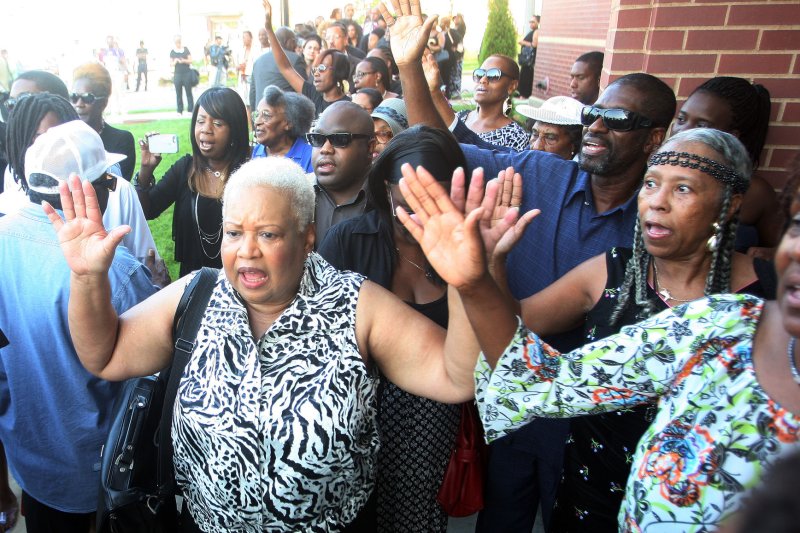 Mourners raise their hands and chant as they wait in line to enter the church for the funeral of Michael Brown in St. Louis. UPI/Bill Greenblatt