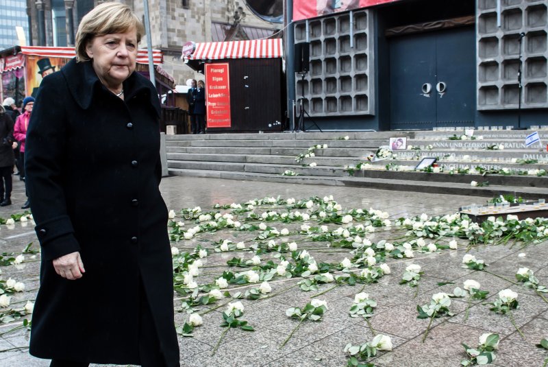 German Chancellor Angela Merkel passes white roses during the commemorative events Tuesday marking the first anniversary of the terrorist attack on Christmas market at Breitscheidplatz in Berlin. Photo by Clemens Bilan/EPA