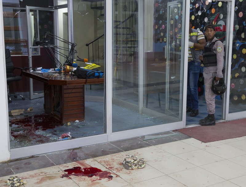 Police in the Dominican Republic investigate the double murder at FM radio station 103.5 in San Pedro de Macoris on Tuesday. Those killed are identified as reporter Luis Manuel Medina, who at the time of the shooting was broadcasting live, and his colleague, Luis Martinez, the director of the station. A secretary, Dayana Garcia, is in serious condition after being shot in the stomach. Photo by Orlando Barria/EPA