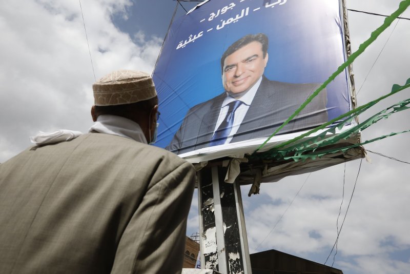 A Yemeni man looks at a billboard depicting Lebanese Information Minister George Kordahi amid a Houthi campaign supporting Kordahi against the policies of Gulf states at a street in Sana'a, Yemen, on Sunday. Photo by Yahya Arhab/EPA-EFE