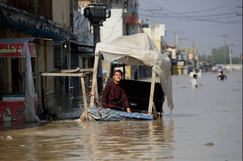 A boy sits on a street stall in a flooded area following heavy rains in Khyber Pakhtunkhwa province, Pakistan, on Monday. Floods triggered by heavy monsoon rains have killed more than 1,100 people across Pakistan since mid-June. Photo by Bilawal Arbab/EPA-EFE