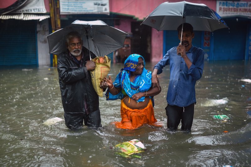Residents evacuate an elderly woman to a safer place through a flooded neighborhood during incessant heavy rains, in Chennai, India, on Thursday. Photo by Idrees Mohammed/EPA-EFE