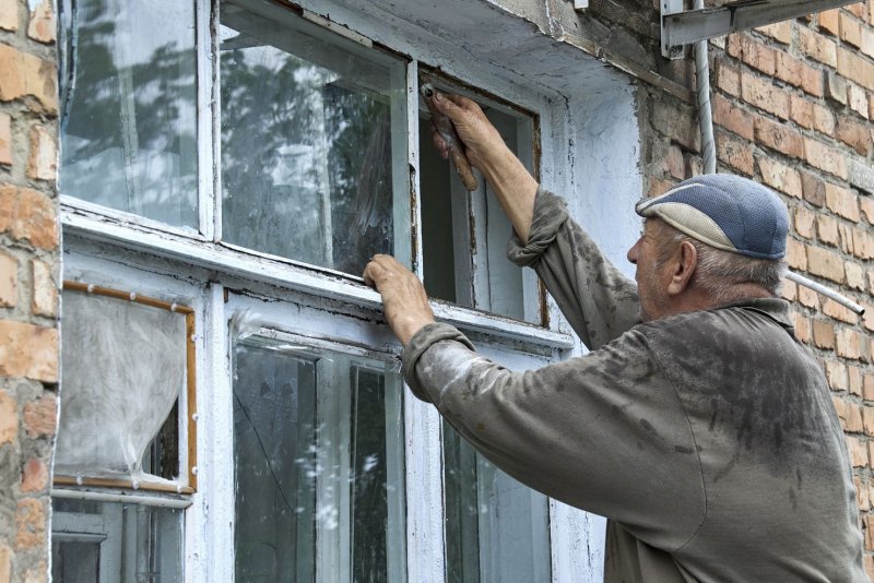 A Ukrainian man changes a window damaged in a missile strike in the city of Chuhuiv near Kharkiv on Saturday. At least three people were killed and lots of buildings destroyed, including a school and some residential buildings, in overnight Russian shelling. Photo by Sergey Kozlov/EPA-EFE