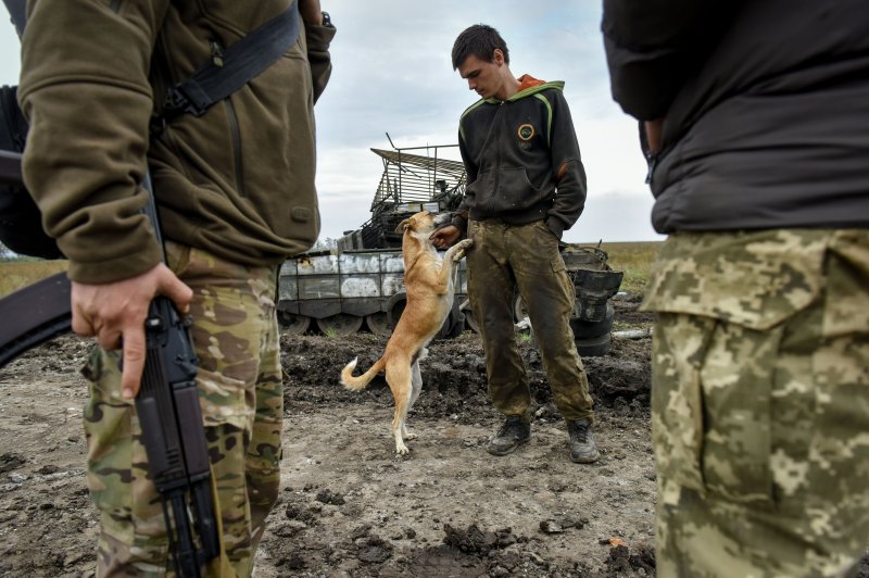A Ukrainian serviceman pets a dog near a captured Russian tank in Kharkiv region of Ukraine on Friday as the Ukrainian army pushed Russian troops from occupied territory in the northeast of the country. Photo by Oleg Petrasyuk/EPA-EFE