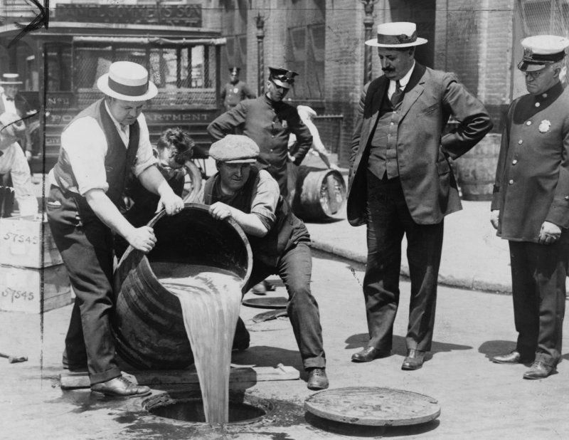 New York City Deputy Police Commissioner John A. Leach, right, watching agents pour liquor into sewer following a raid during the height of prohibition. File Photo by Library of Congress/UPI