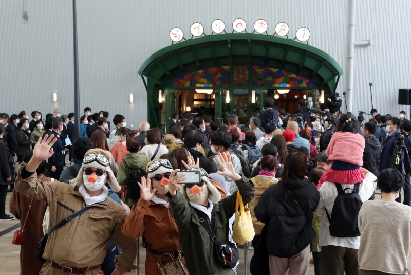 Visitors, wearing masks and custumes, line up at the entrance of Ghibli's Grand Warehouse for the grand opening of Ghibli Park in Nagakute, central Japan, on Tuesday. The theme park is split into five areas inspired by Studio Ghibli’s most famous films: Hill of Youth, Ghibli’s Grand Warehouse, Dondoko Forest, Mononoke’s village and the Valley of the Witches. There aren't any rides or attractions, but visitors can “take a stroll, feel the wind and discover the wonders” of films. Photo by JiJi Press/EPA-EFE