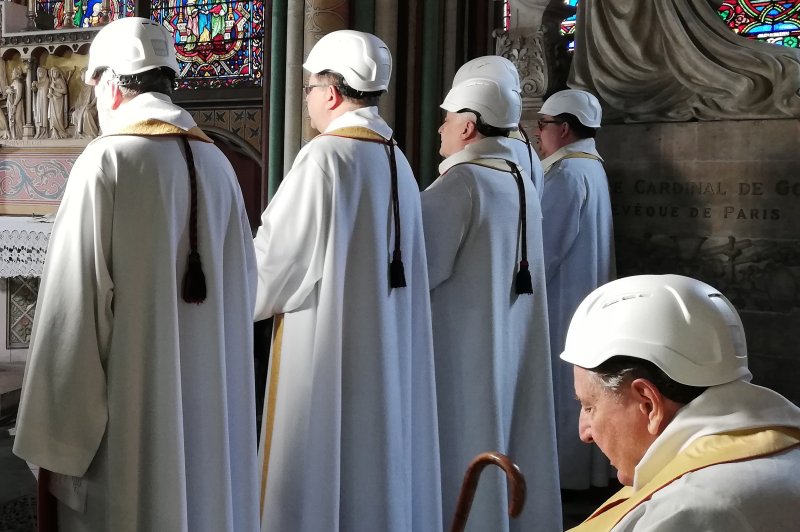 Clerics wear protective helmets Saturday as they attend a mass led by Archbishop of Paris Michel Aupetit at Paris' Notre Dame cathedral. The service was the first held in the structure since a fire exactly two months earlier. Pool Photo by Karine Perret/EPA-EFE