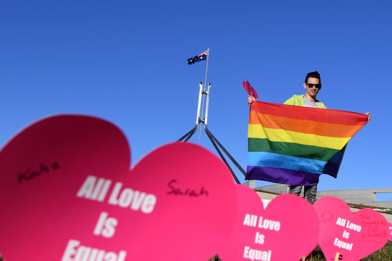 A marriage equality advocate poses for a photograph with a rainbow flag during the "Sea of Hearts" event outside of the Parliament House in Canberra, Australia, on Tuesday. Photo by Lukas Coch/EPA