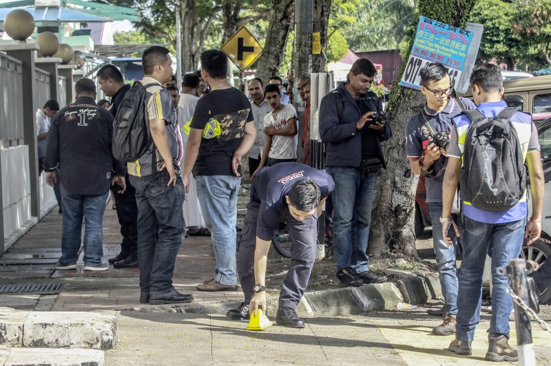 Royal Malaysian Police forensic officers collect evidence at the crime scene where a Palestinian scientist, Fadi Mohammad al-Batsh, 35, was reportedly assassinated in a drive-by motorcycle shooting Saturday in Kuala Lumpur, Malaysia. Photo by EPA